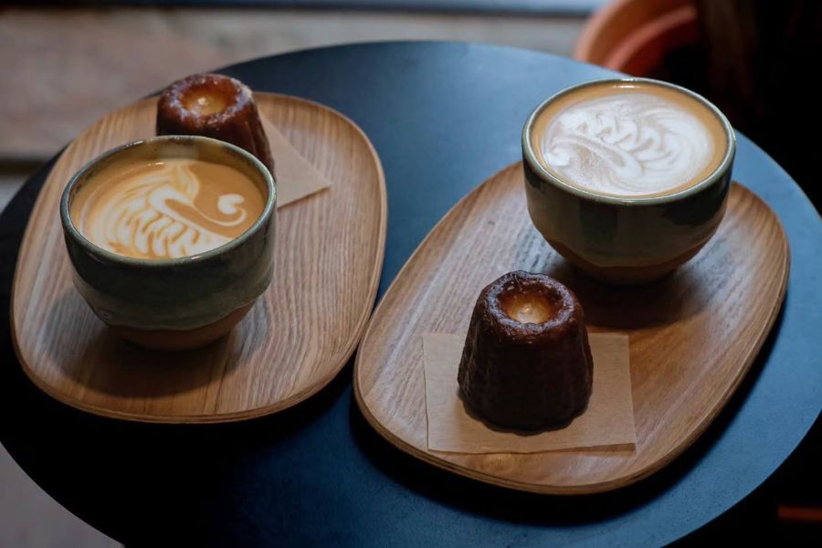 Two flat whites and a slice of chocolate cake on a tray on a dark table, Cambridge